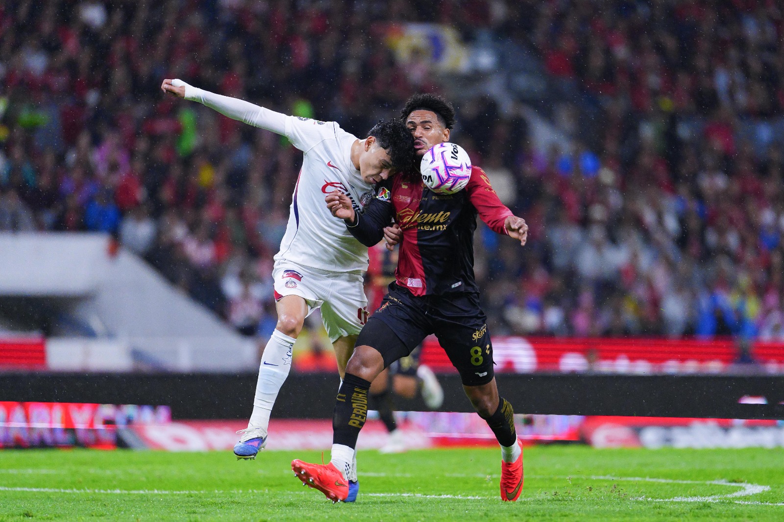 Un jugador de Chivas disputa el balón por aire ante un futbolista del Atlas durante el Clásico Tapatío del Apertura 2026.
